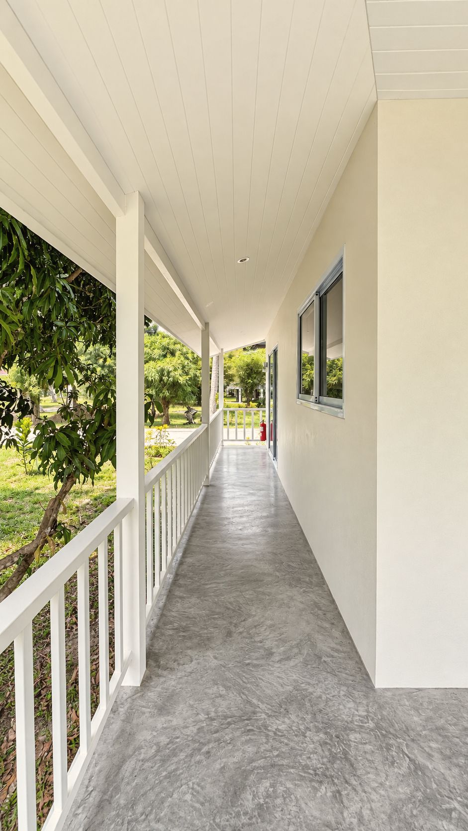 Long white veranda with railings running alongside the bungalow