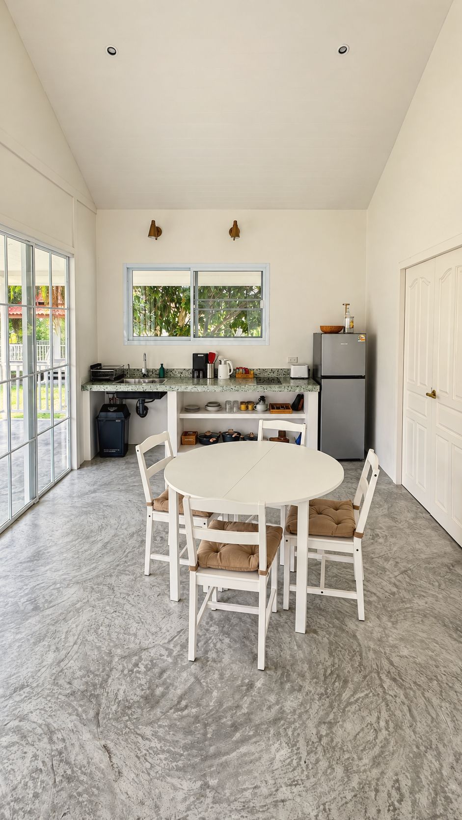 Open living and dining room with round white table and kitchenette